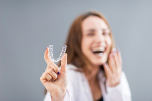 smiling Turkish woman is holding an Invisalign Bracer