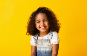 Happy African-american Girl Child smiling to camera over yellow background