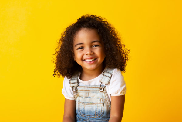 Happy African-american Girl Child smiling to camera over yellow background