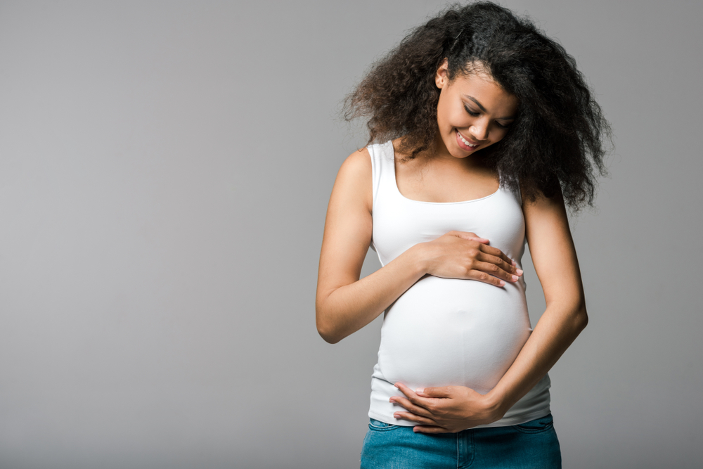 Pregnant woman gently holding her baby bump, representing orthodontic treatment considerations during pregnancy