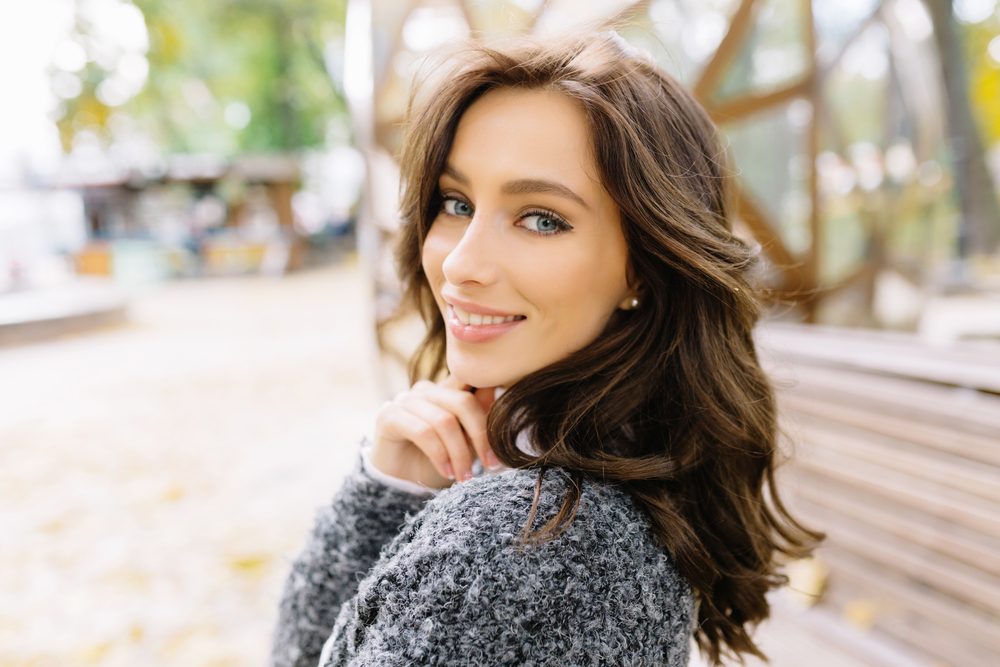 Smiling woman outdoors with healthy teeth representing orthodontic treatment and dental care benefits in Canada