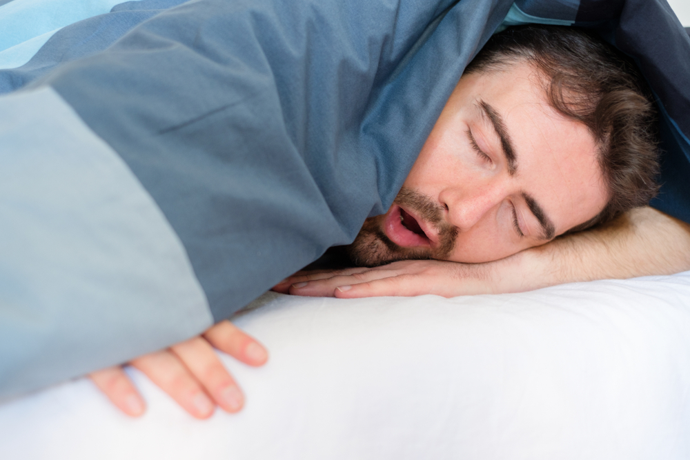 Man sleeping with his mouth open, a possible sign of sleep apnea